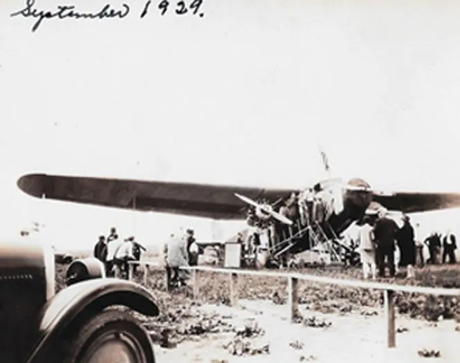 Sepia image of the 1929 Monarch Food Shipment Plane with a crowd around it